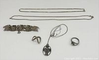 Photo showing full lot with vintage style sterling silver bracelet featuring owl motifs, two rings of different designs, oval religious pendant necklace, and two silver chains.