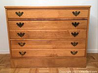 Front view of Vilas wooden dresser with five drawers, light wood finish, and dark metal handles.