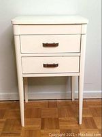Front view of white two-drawer sewing cabinet with tapered legs