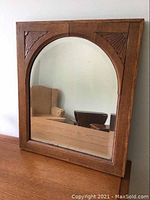 Full front view of oak-framed mirror with arched top on desk