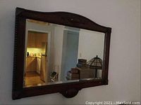 Full front view of mirror hung on wall reflecting kitchen and lamp
