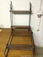 Photo of two wooden and cast iron shelving units showing overall structure and condition with shelves horizontal and base section visible.
