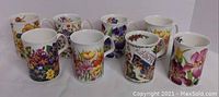 10 Roy Kirkham bone china mugs arranged in two rows showing variety of colorful floral and dog patterns.