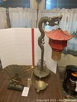 Full display of the Asian decor items including dragon lamp, brass fan, brass dish, and tower figurine on table.