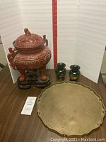 Lot overview showing brass plate, urn with wood base, and two small vases