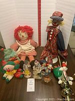 Lot containing handmade Raggedy Ann doll and multiple ceramic clown figurines displayed on a table.