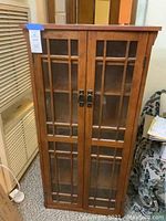 Front view of wood display cabinet with closed glass paneled doors.