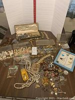 Assortment of costume jewelry on display including boxed sets, necklaces, bracelets, rings, and clip-on earrings.