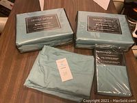 Two packaged Hotel Style 600 thread count full size sheet sets and one unpackaged light blue sheet folded with tag