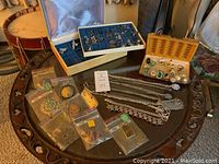Full view of the assortment of costume jewelry including boxes with earrings and rings, necklaces laid on table, and some items in plastic bags.
