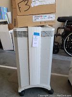 Front view of IQAir air purifier, showing tall, vertical design with vented panels on sides and front center piece.