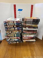 Photo showing a stack of assorted DVDs with JAG seasons 1-10 prominently displayed alongside various movie DVDs including MASH and Battleground.