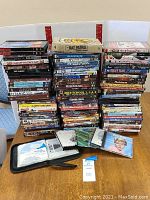 Photo showing large stacks of assorted DVDs and some CDs in jewel cases laid out on a table