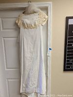 Front view of the vintage linen wedding dress showing lace detail on cap sleeves and bodice, long skirt hanging straight down.