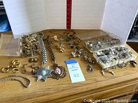 Overview of costume jewelry pieces laid out including earrings, rings, pendants, and necklaces in gold and silver tones.