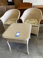 Front view of two wicker chairs and matching side table with glass top