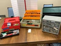 Four boxes and organizers containing tools and hardware on a wooden table