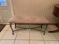 Front view of bench showing beige microfiber padded top and silver metal legs with cross supports.