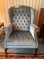 Front view of the blue tufted wingback chair with detailed upholstery and nailhead trim.