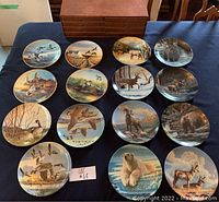 Photo of all 15 wildlife-themed collector plates laid out in rows on a surface, showing a variety of animals and natural scenes.