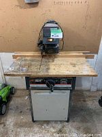 Front view of Sears Craftsman table saw showing blade, base, and wood work surface with wear.