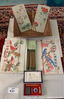Overall view of the set showing the decorative plaques and printed fabrics with birds, and the boxed ink brush set