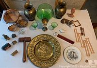 Wide view of multiple decor items on a table including vases, bowls, figurines, decorative plate, and glassware.