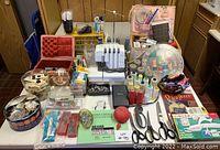 Wide view of serger on table with thread spools, scissors, pincushion and accessories around