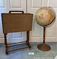 Overview of four folding TV trays nested in matching metal stand beside Replogle floor globe on pedestal