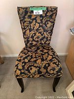 Front view of single black and tan patterned fabric upholstered chair, showing overall design and label with measurements.