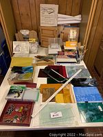 Wide overview of table showing sheets of stained glass, hand tools, wooden frames and power equipment
