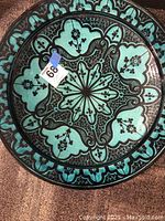 Overhead view of large round decorative bowl with black and turquoise pattern