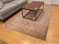 Full view of the Pottery Barn wool handwoven floor rug under a coffee table and next to a sofa