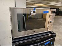 Front view of Panasonic stainless steel microwave with dark window and control panel on right.