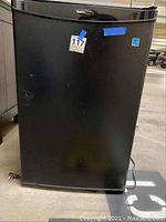 Frontal view of black Danby portable refrigerator, showing logo and door with minor marks.