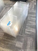 Stack of clear acrylic lucite office organizers placed on carpeted floor, showing overall size and thickness.