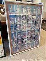 Framed Marilyn Monroe multi-image pin-up poster showing a grid of various poses of Marilyn Monroe in light outfits, with some poses outdoors and others in studio settings.