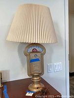 Full view of the lamp with shade on tabletop against wall.