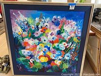 Front view of colorful abstract floral acrylic painting in wood frame with blue mat