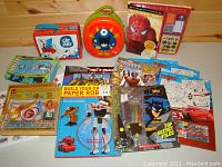 Overview photo showing all items in the lot including activity books, lunch boxes, and pencil cases arranged together