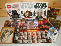 Group shot of Star Wars books, toy figures, playing cards, pins collection, and display items.