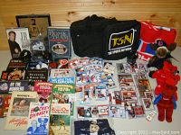 Wide shot showing entire sports lot with hockey cards, books, duffle bag, blanket, plush toys, and collectible car