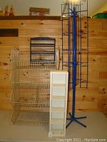 Photo showing metal wire basket racks along with blue standing rack and white wooden cubby shelf on a table against a wood-paneled wall