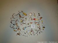 Top-down view of various vintage fishing lures, spinnerbaits, fishing spoons, treble hooks, and a fishing bobber spread on a white surface