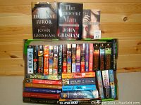 Books including The Last Juror, The Innocent Man by John Grisham, and Mr. Mercedes by Stephen King with various paperback and hardcover books beneath, including Star Wars and sci-fi titles