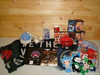 Photo of Toronto Raptors flags, Raptors floor mat, Ottawa Senators cap, mug, VHS tapes, Muhammad Ali pillows, baseballs, and plush toys arranged on floor against wooden wall