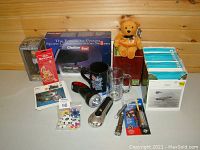 Photo of entire box lot showing all items described including Chatter Box, poker chips, flashlights, cigar box, bear, bobblehead, and cards.