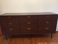 Front view of large walnut dresser with 9 drawers, showing metal handles and tapered legs