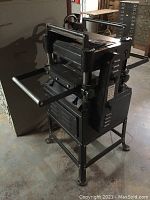 Side view of PowerMaxx 15" planer with stand showing infeed/outfeed tables and depth adjustment wheel