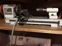 Side view of bench lathe showing headstock, bed, carriage and tailstock